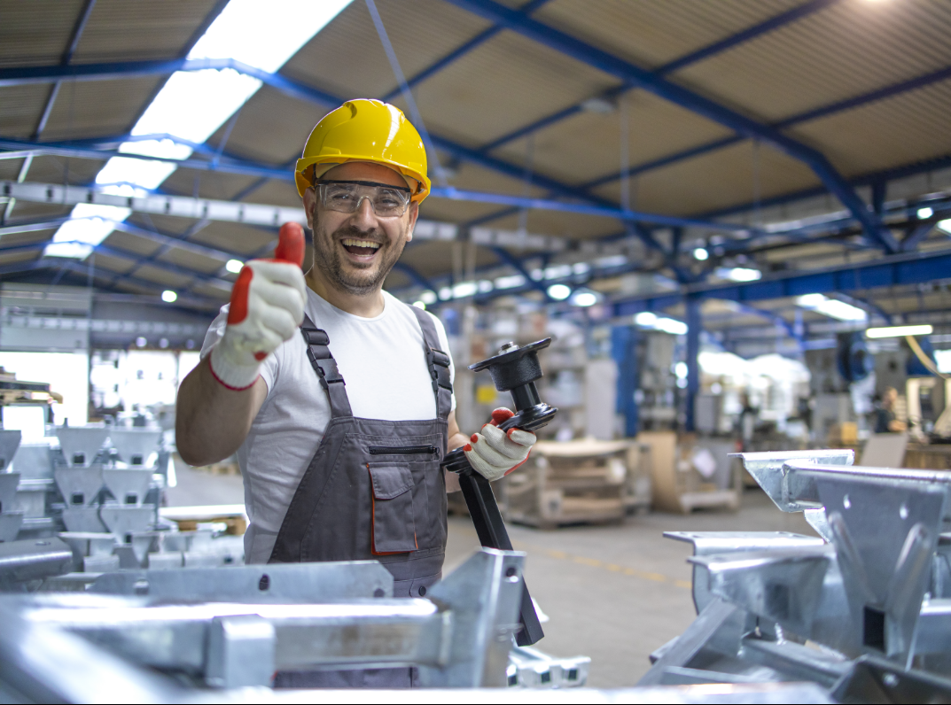 portrait factory worker protective equipment holding thumbs up production hall e1645594807877